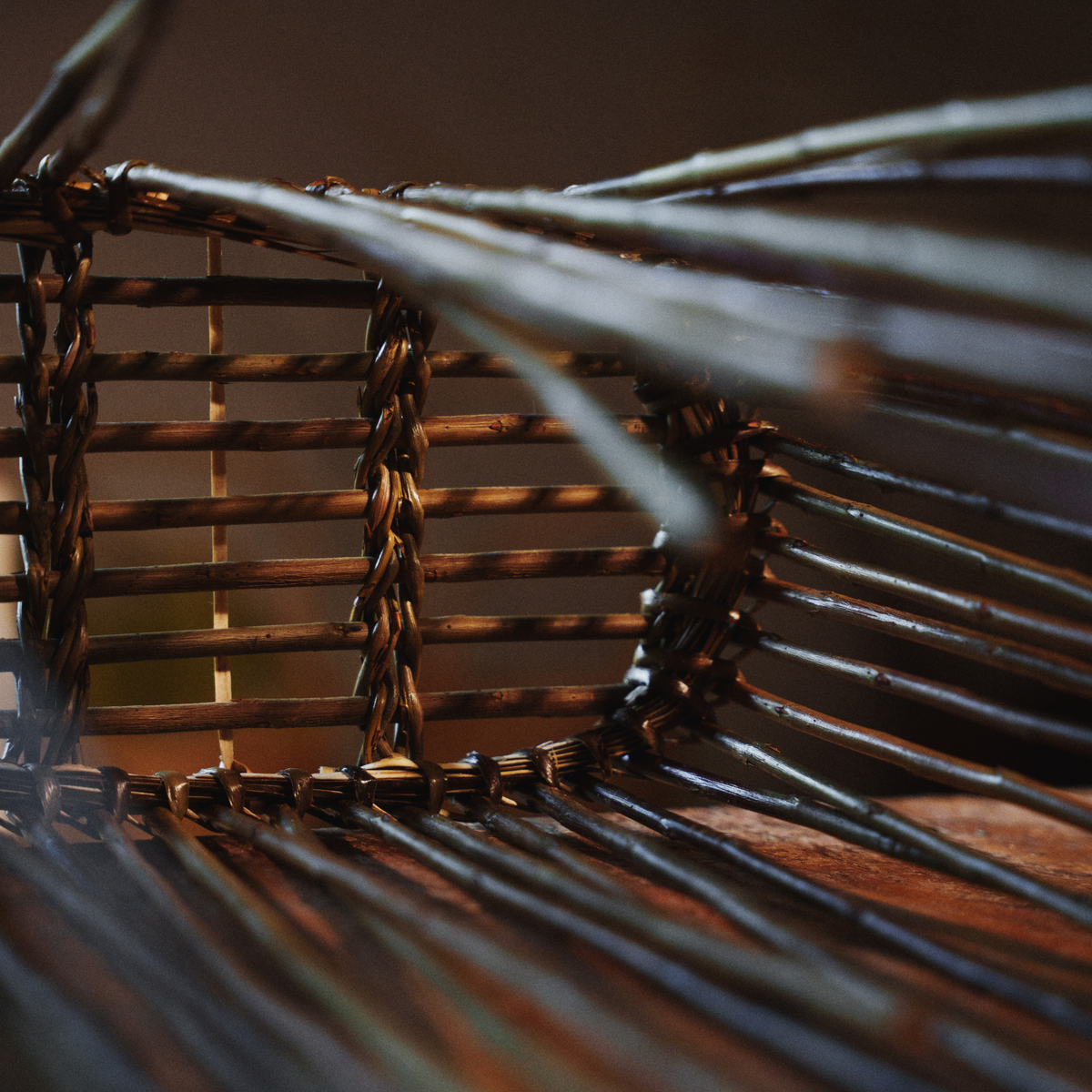 Close-up of a dark brown woven basket or chair frame with tightly bound slats and blurred foreground elements.