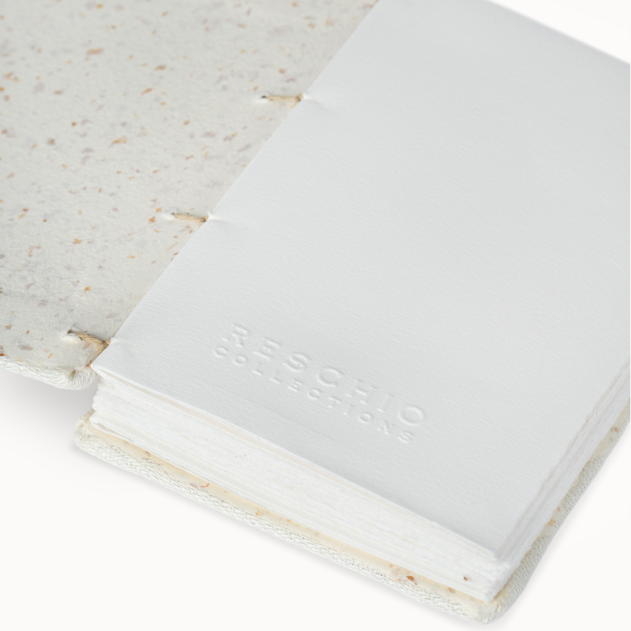 A close-up of a white notebook or journal with a speckled off-white cover, showing the debossed brand name 'RESCHIO COLLECTIONS' on the front.