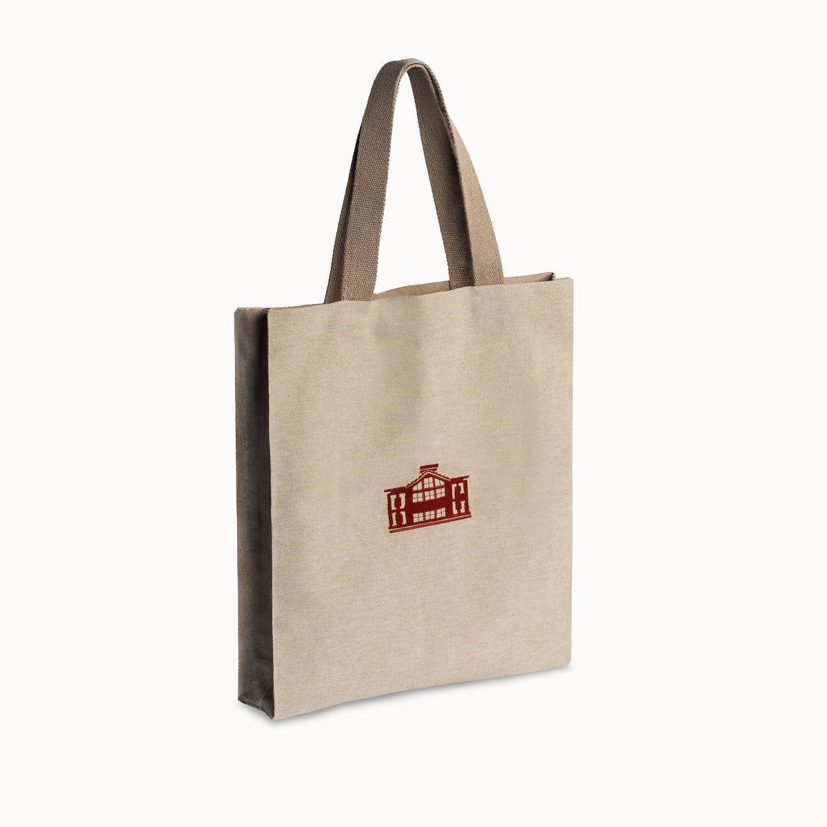 A natural beige canvas tote bag with dark brown handles and a small red printed graphic on the front, shown on a clean white background.