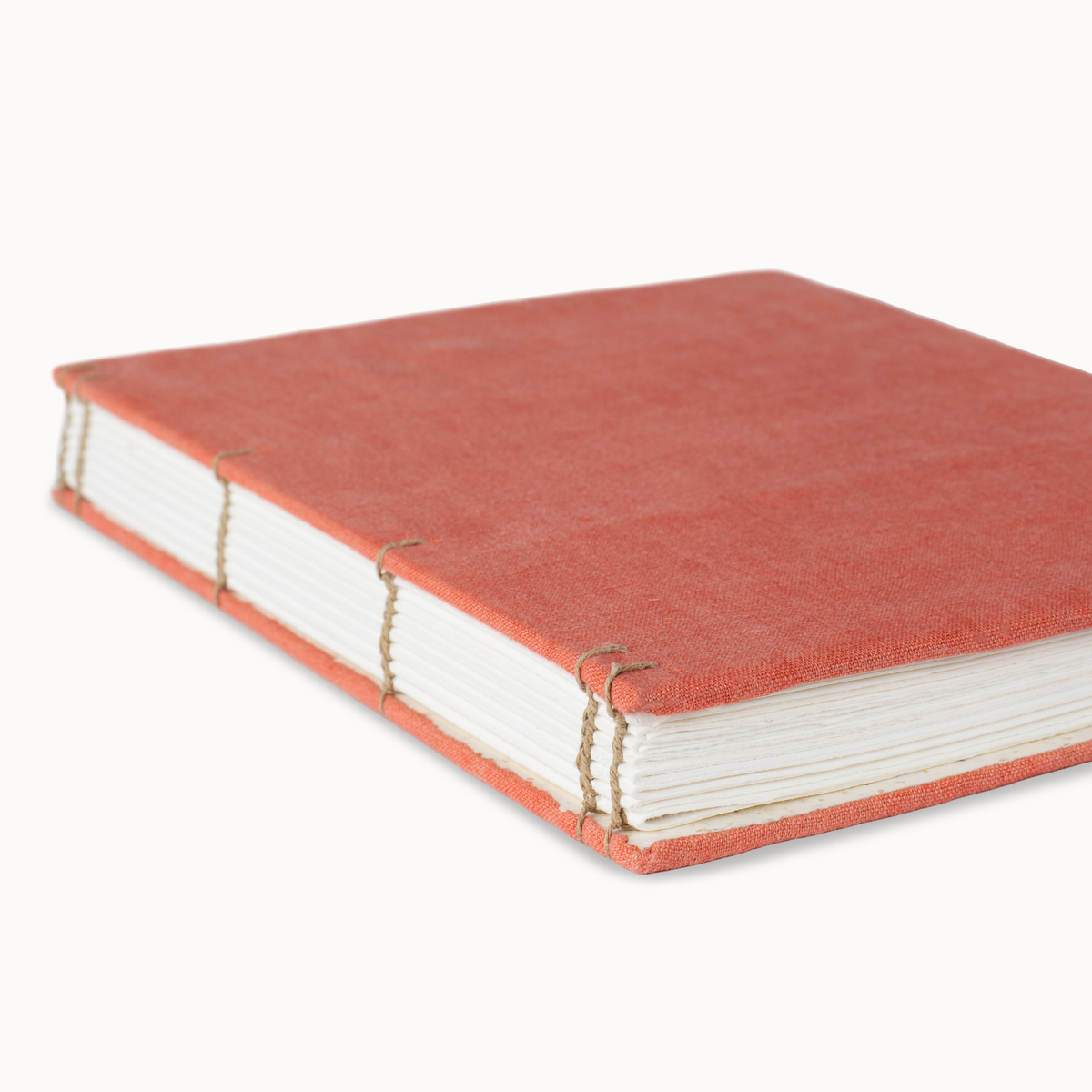 A handmade hardcover book with a textured coral-orange linen cover, white paper pages, and visible thread binding on a clean white background.